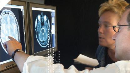 Doctor reviews brain scan image with female patient at Prescan, Vienna